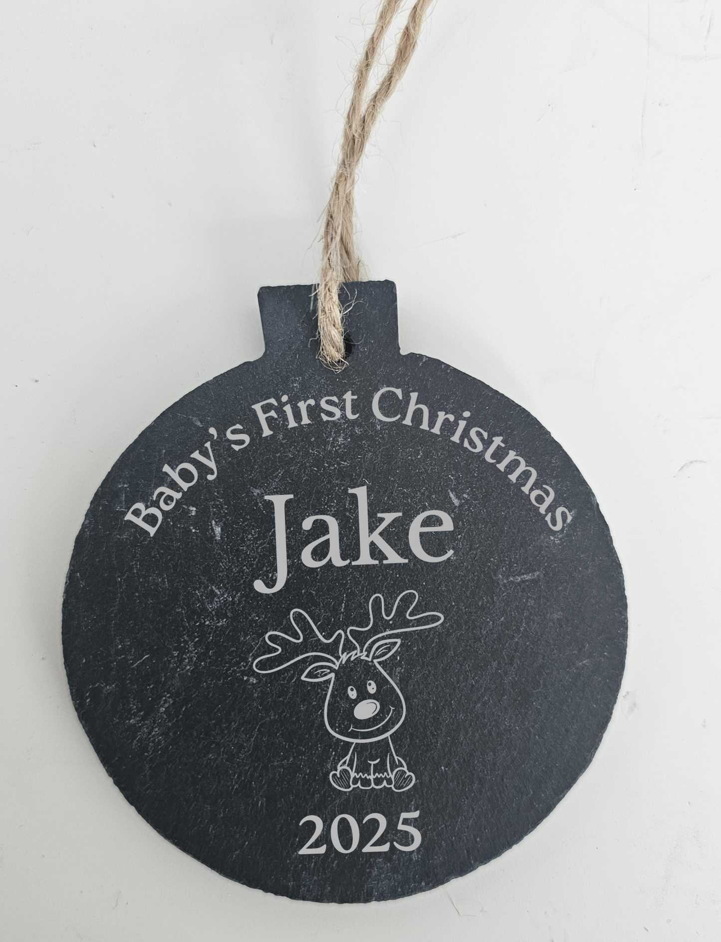 Round slate ornament with 'Baby's First Christmas Jake 2025' text on a white background