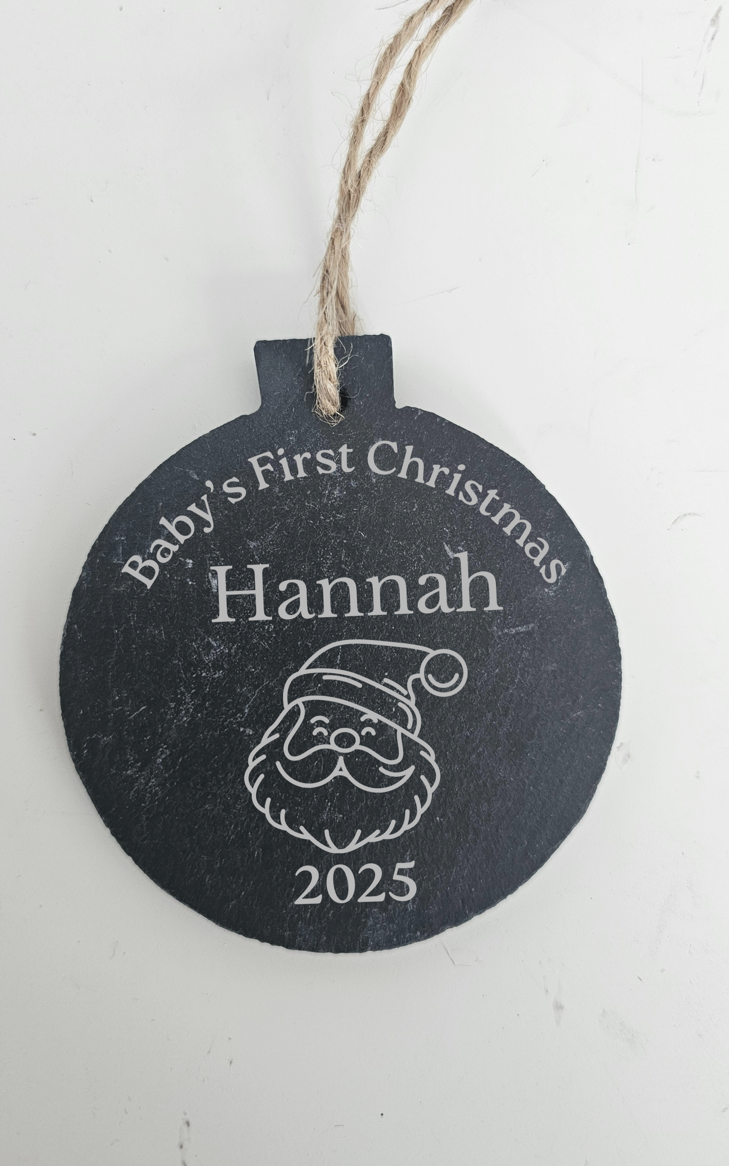Decorative Christmas ornament with 'Baby's First Christmas Hannah 2025' text on a white background