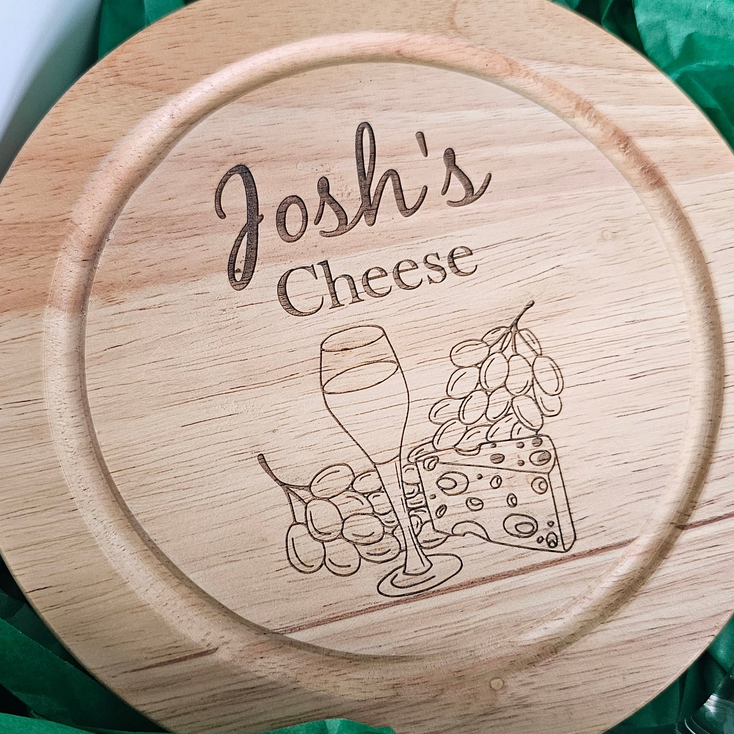 Wooden cheese board with 'Josh's Cheese' engraving and a graphic of a glass of wine and cheese.