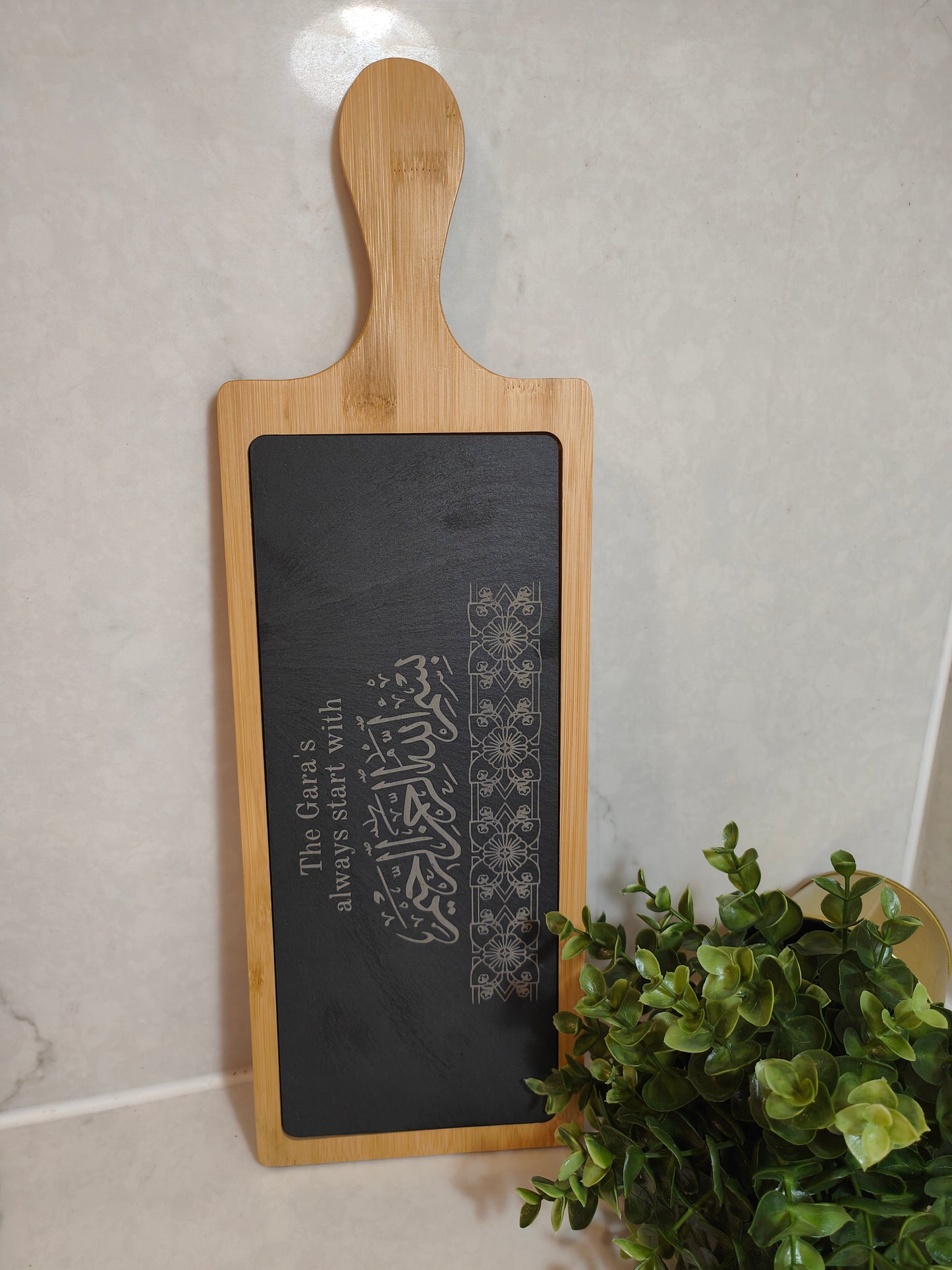 wooden and slate serving board standing against the wall with arabic calligraphy