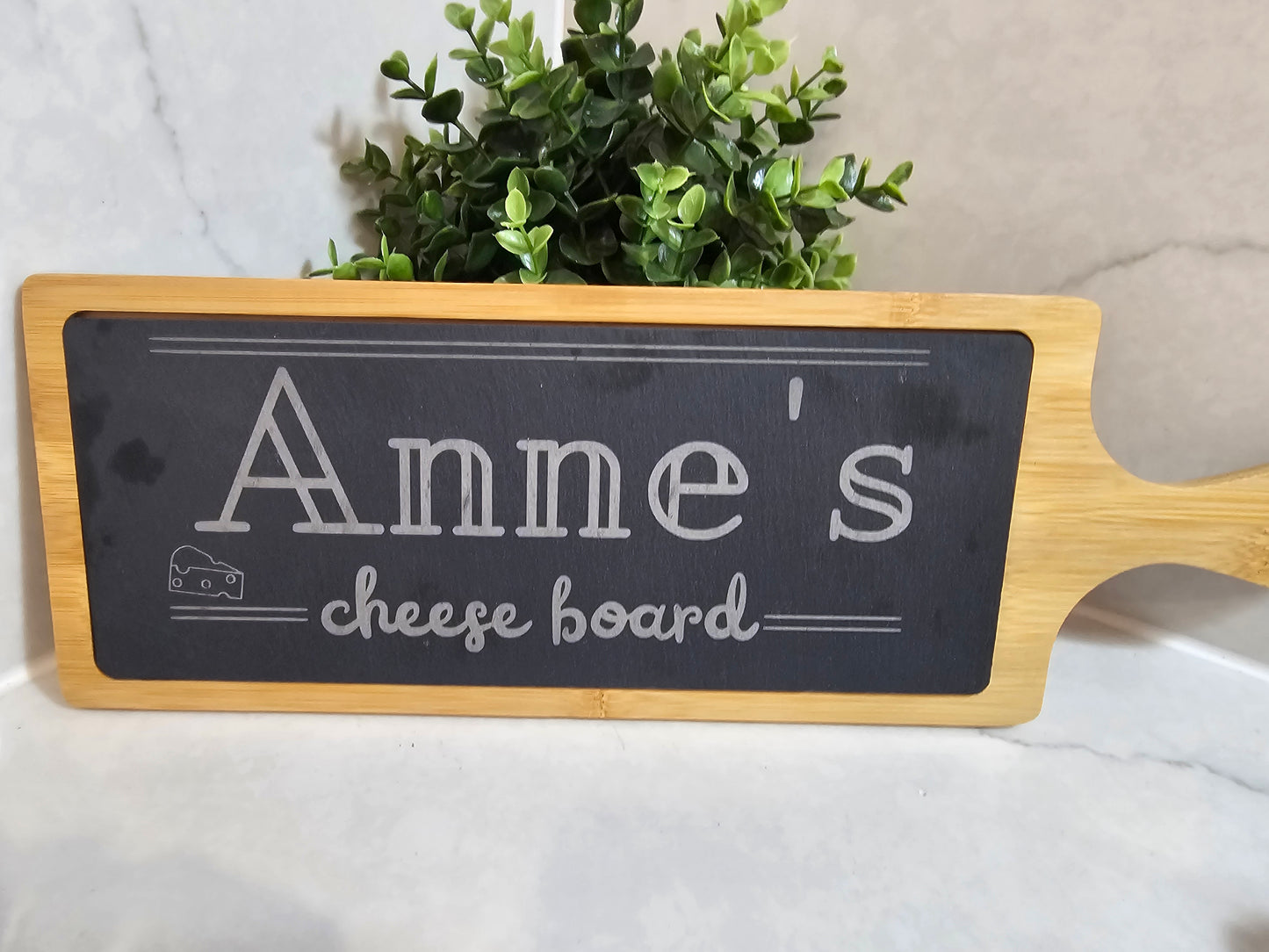 Cheese board with black chalkboard surface and wooden handle, featuring 'Anne's cheese board' text.