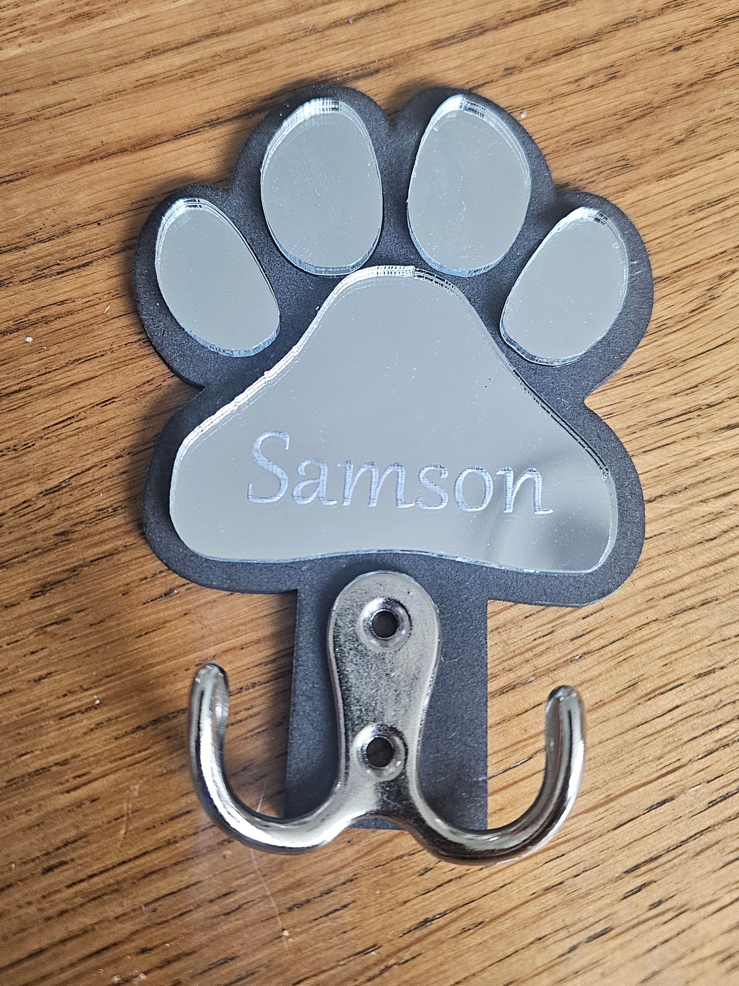 Paw-shaped hook with 'Samson' engraved on a wooden surface