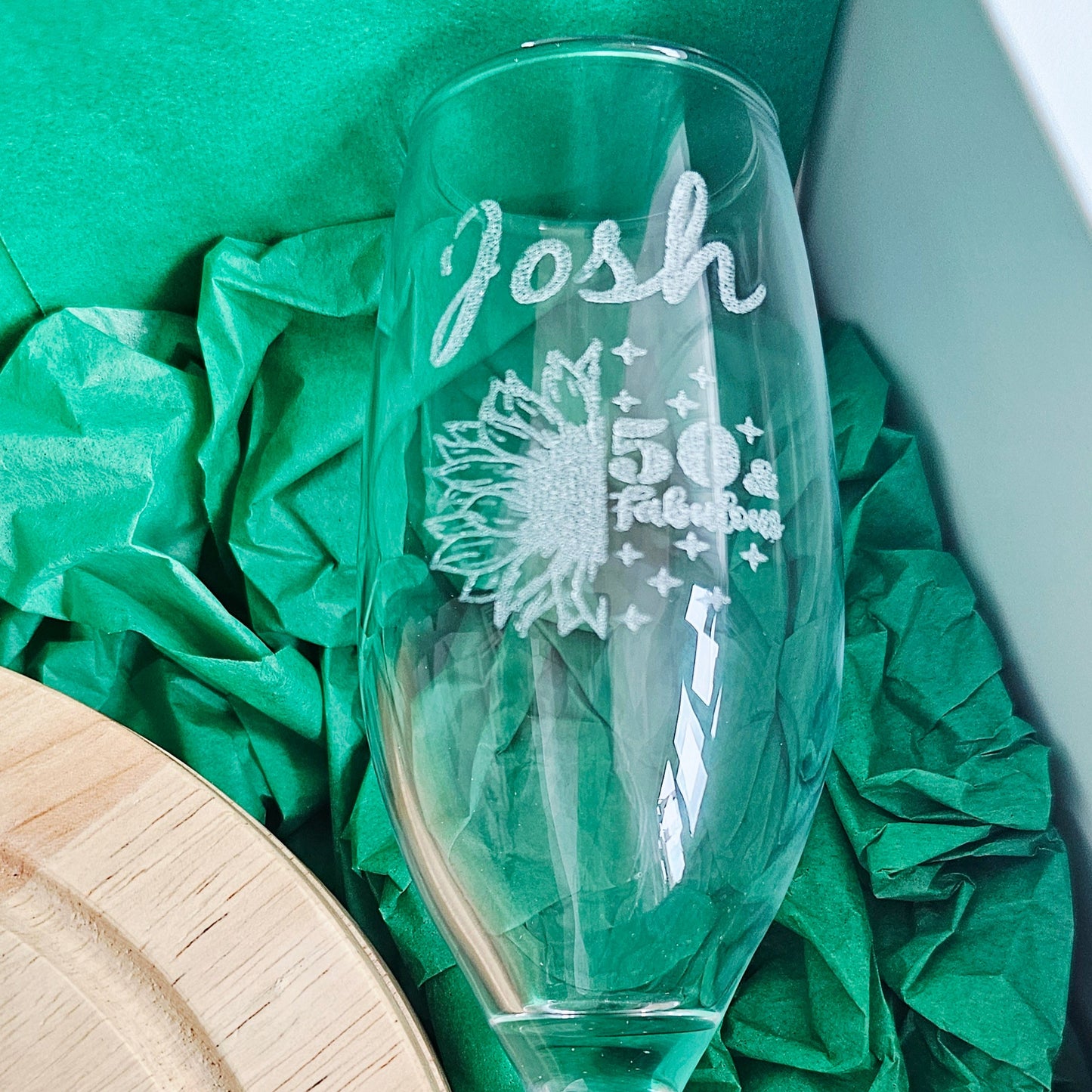 Clear glass with engraved design and text on green tissue paper