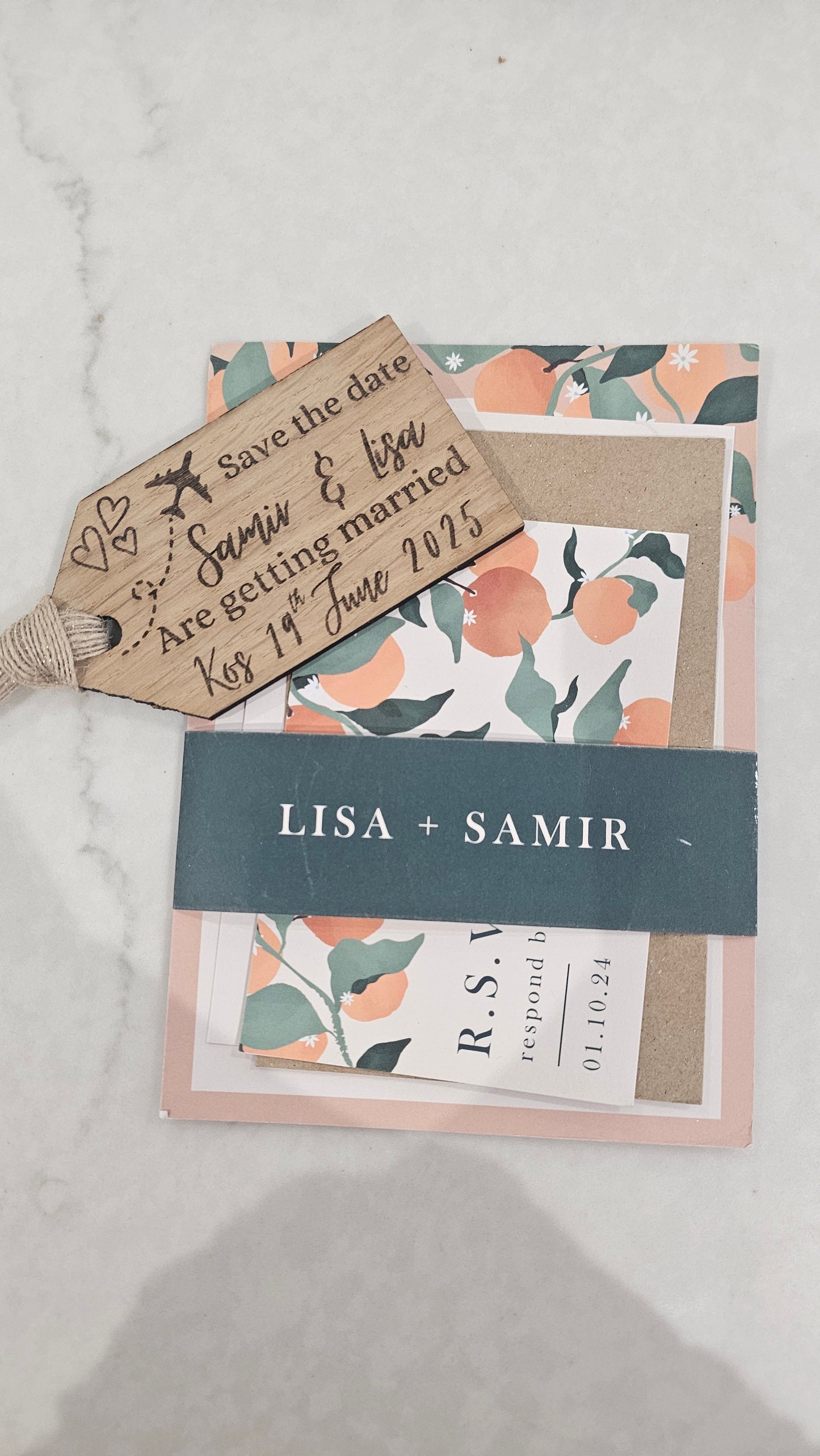 orange white an green wedding invitation with a wooden luggage tag engraved with wedding details