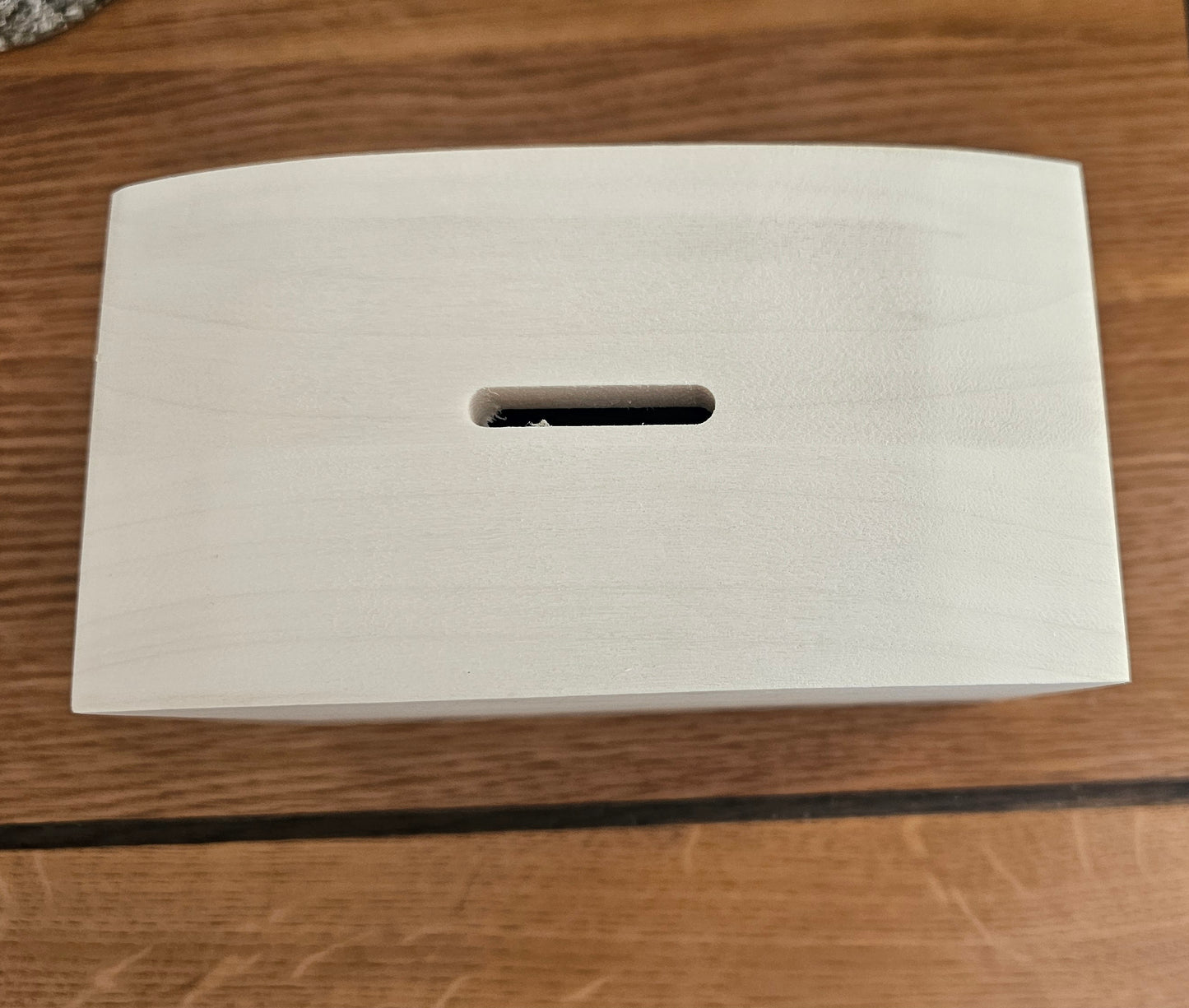 White rectangular box with a cutout handle on a wooden surface