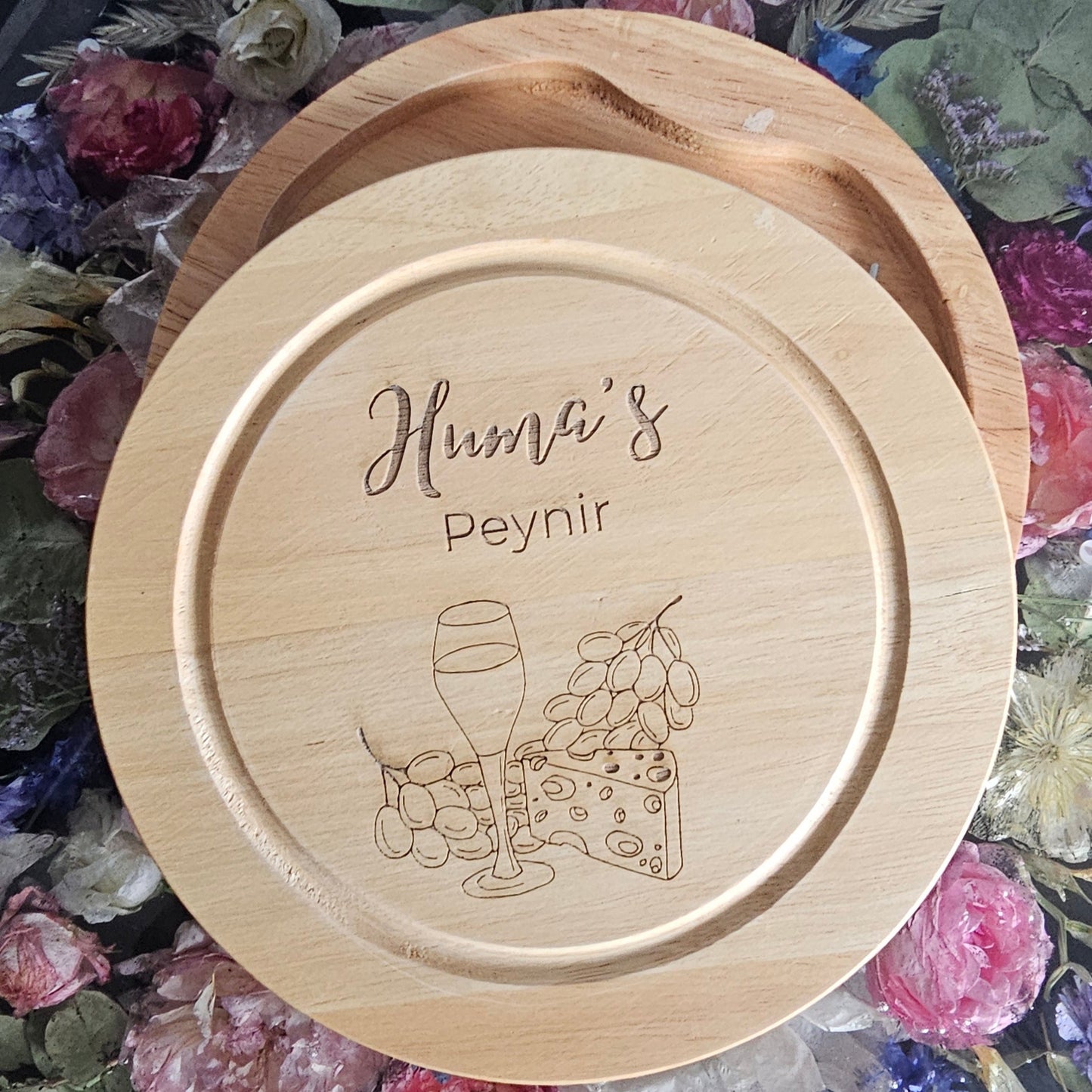 Personalised Wooden cheese board with engraved design and text on a decorative tablecloth with flowers.