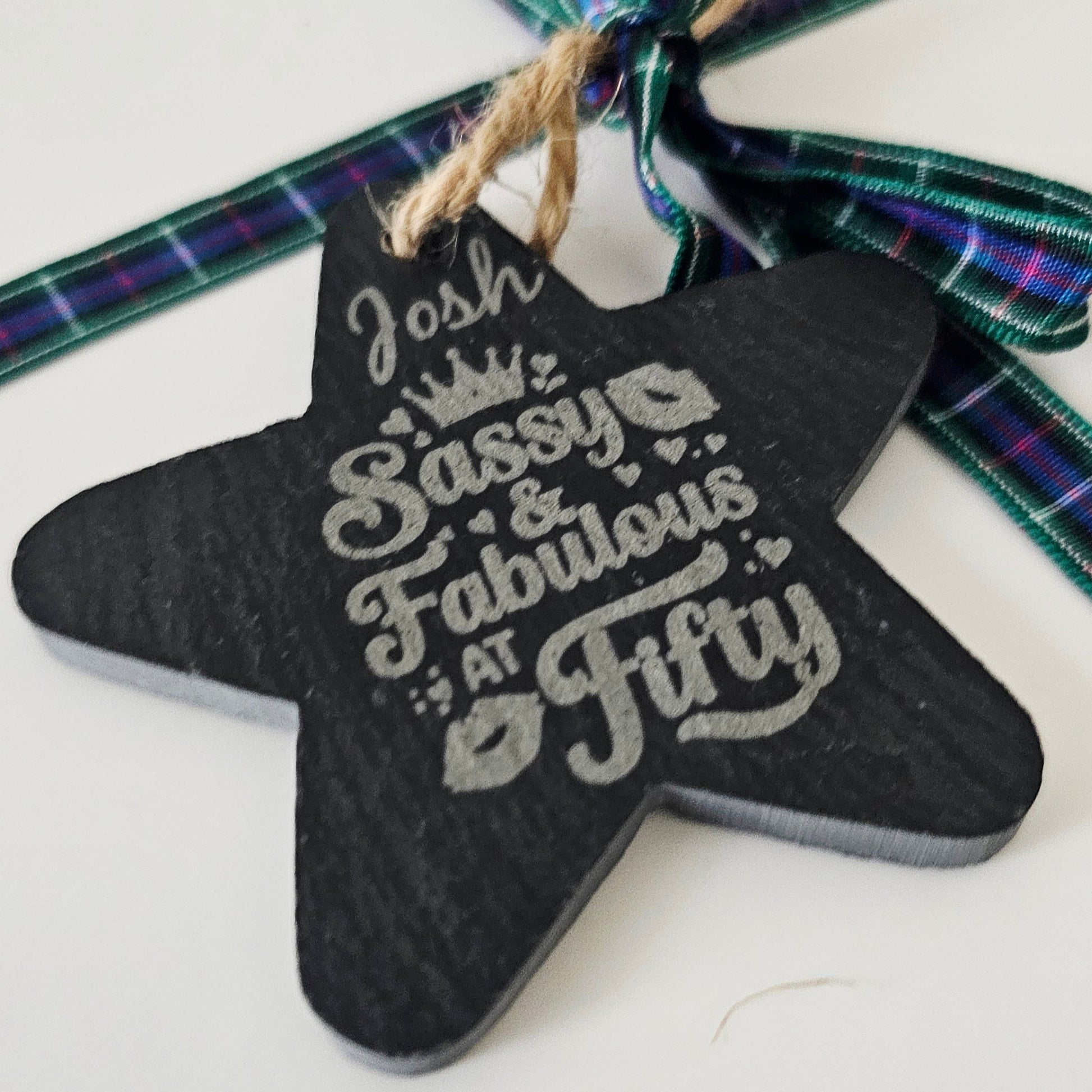 Star-shaped ornament with 'Josh Sassy & Fabulous at Fifty' text on a tartan background