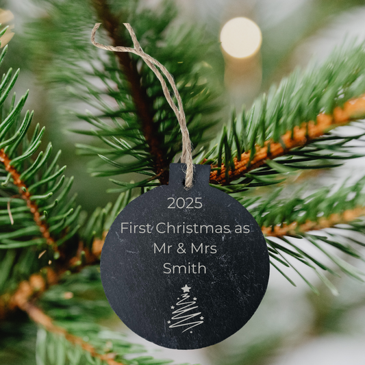 Personalized Christmas ornament tag on a tree branch with '2025 First Christmas as Mr & Mrs Smith' text.