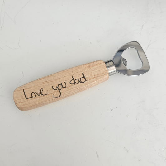 Bottle opener with wooden handle and hand written 'Love you dad' message engraving on a white background