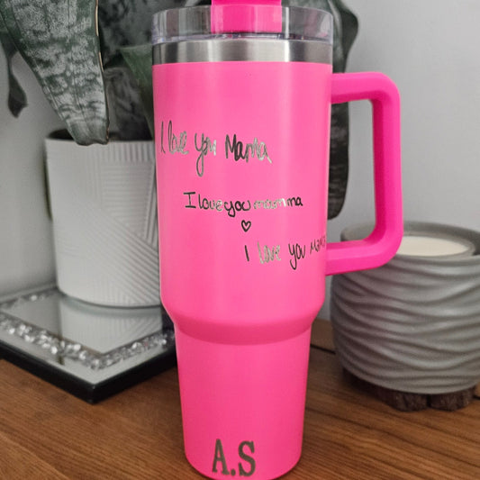 Pink thermos with handle and hand written personalised message engraved on it on a wooden surface