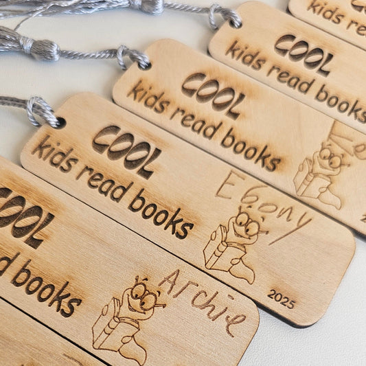 Personalised wooden bookmarks engraved with “Cool kids read books” and a bookworm illustration, featuring children’s handwritten names and tassels, custom teacher gifts or student reading rewards.